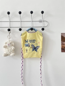 Détail du sac en toile jaune avec broderie papillon et poignée en corde tressée colorée