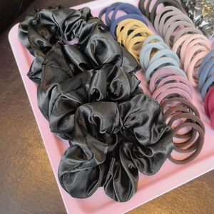Detail of silk scrunchies and colorful elastic hair bands set in a pink organizer tray