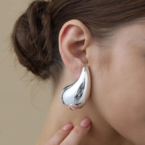 Minimalist silver teardrop earrings in polished stainless steel shown on a model