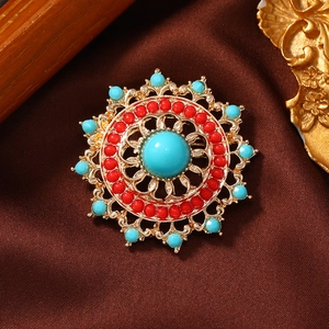 Vintage hollow geometric brooch with turquoise and coral beads on silk fabric