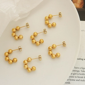 Three pairs of retro 18k gold-plated C-shaped beaded earrings on a white plate