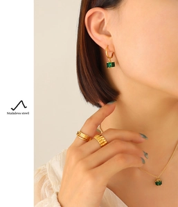 Close-up of gold stainless steel jewelry set featuring square green emerald zircon accents
