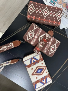 Three Aztec geometric print canvas wristlet wallets in various sizes on wood background