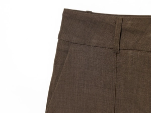Macro detail of high-waist dark brown trousers showing twill fabric and belt loops