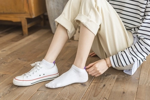 Detail of white cotton low-cut socks with heart heel design worn with canvas shoes