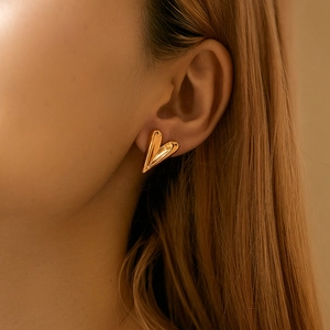 Close-up of a model wearing minimalist irregular gold heart-shaped stud earrings