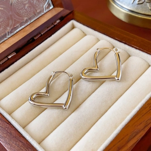 Boucles d'oreilles créoles cœur creux argentées dans un écrin en bois et velours
