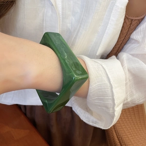 Close-up of green marble acrylic bangle with unique geometric texture on a wrist