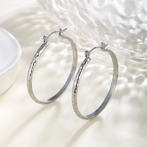 Close-up of silver hoop earrings featuring artistic hammered texture on metal surface