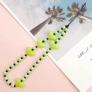 Detail showing green heart acrylic beads and striped resin spheres on a DIY phone strap