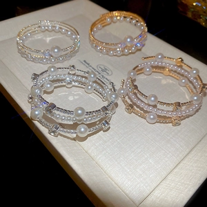 Detail of layered gold and silver bracelets with pearls and rhinestones on a display box