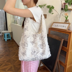 Detail of white canvas tote bag featuring butterfly print and 3D fringe texture