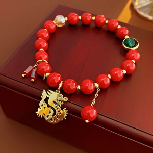 Gros plan d'un bracelet en perles rouges avec pendentif dragon chinois doré et détail Fu