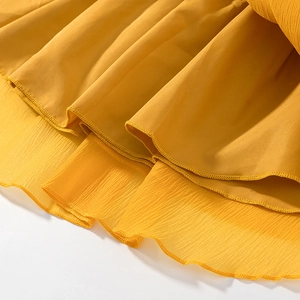 Detail of ginger yellow chiffon fabric featuring delicate ruffled edges and layered textures