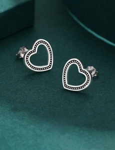 Detail showing S925 sterling silver heart-shaped stud earrings on green velvet surface