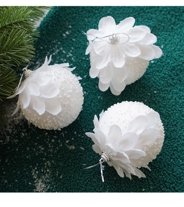 Close-up of white petal-covered Christmas ornaments with foam texture on green pine