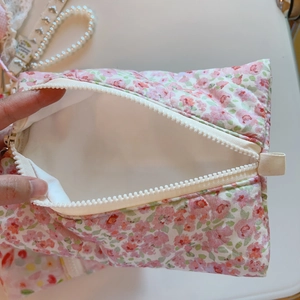 Détail de la pochette matelassée en coton fleuri rose avec fermeture éclair blanche