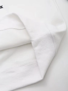 Detail of white rib-knit hem and RK text embroidery on casual loose long sleeve sweatshirt