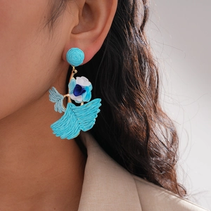 Detailed view of blue woven bird-shaped floral earrings on a female model with soft lighting
