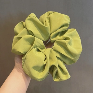 Handheld light green oversized scrunchie made of pleated chiffon fabric for hair styling