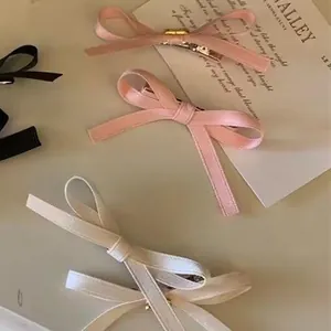 Detailed view of layered ribbon bow hair clips in pink, cream, and black colors