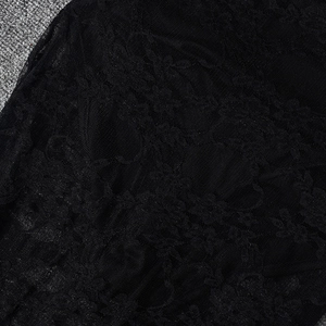 Detailed close-up of intricate hollow lace patterns on a black backless jumpsuit