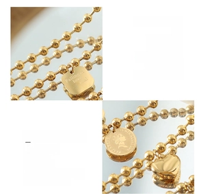 Close-up of 18K gold plated titanium steel bead bracelet with engraved coin and heart charms