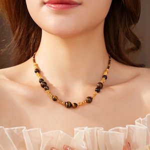 Détail du collier en perles d'oeil de tigre avec accents dorés sur le mannequin