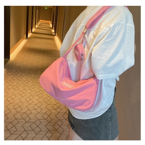 Detailed view of pink nylon crescent bag with mini coin purse on a shoulder strap