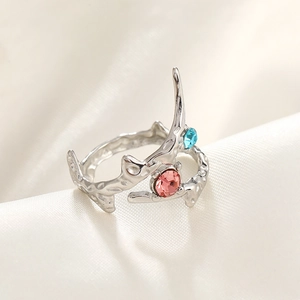Macro shot of silver hammer-textured branch ring with blue and pink gemstones