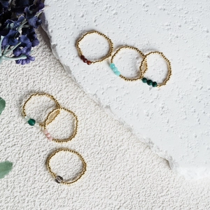Detail of colorful stone beads and golden beads on elastic minimalist rings