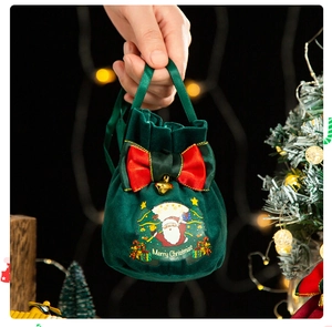 Detail of dark green velvet Christmas gift bag with a red bow and festive Santa Claus print
