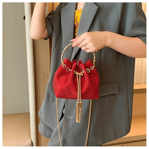 Detail of red rhinestone bucket bag featuring gold ring handle and drawstring tassels