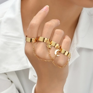 Detailed view of gold star and moon charms on a multi-finger chain bracelet ring set