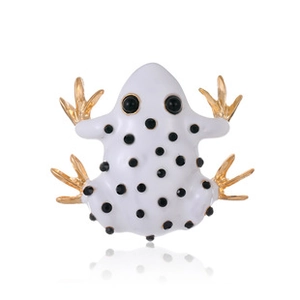 Macro shot of white enamel frog brooch with black polka dots and gold-plated limbs
