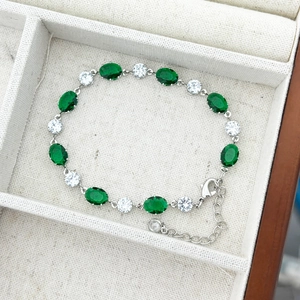Vue détaillée du bracelet argenté orné de pierres émeraude ovales et de zircons blancs