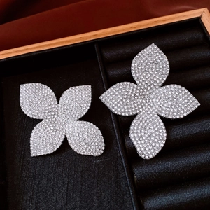 Vue détaillée de deux boucles d'oreilles fleur argentées avec cristaux sur plateau velours