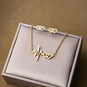 Detail of gold heartbeat and double heart necklace set displayed on jewelry box