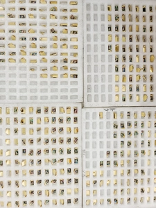 Close-up of gold stainless steel rectangular pendants with colorful shell alphabet inlay