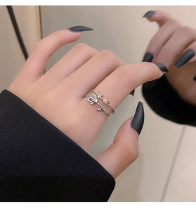 Detailed view of a silver rose ring with thorn design worn on a finger with mirror reflection