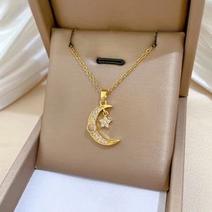 Détail du pendentif lune et étoile doré serti de zircons brillants sur un écrin luxe