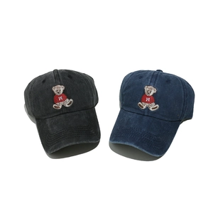 Detailansicht von gewaschenen Jeans-Baseballkappen mit Bärenstickerei in Grau und Blau