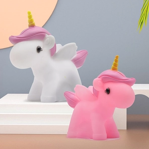 Cute pink and white unicorn night lights with golden horns on a white display stand