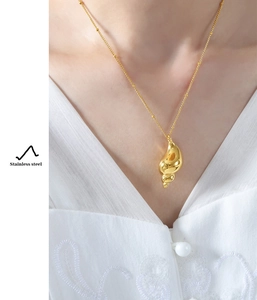 Macro shot of gold stainless steel conch pendant necklace on satellite bead chain