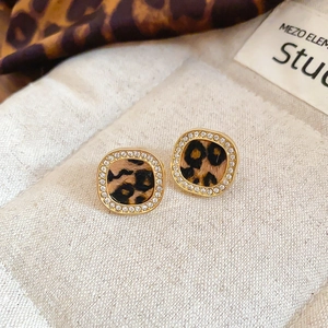 Macro shot of gold square stud earrings with leopard print inlay and sparkling rhinestones