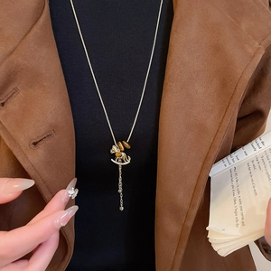 Detail of a rocking horse pendant necklace featuring tiger eye stone and elegant tassels