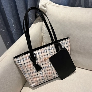 Classic check pattern tote bag with matching black pouch on a soft beige sofa
