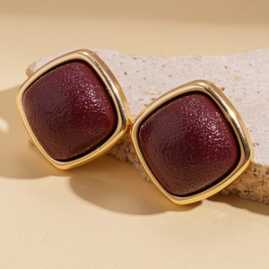Macro shot of vintage square gold stud earrings with deep red pear-skin texture detail