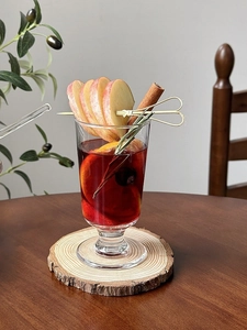 Detail of mulled wine in a glass with apple slices, cinnamon sticks and rosemary