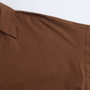 Detailed macro view of the brown poplin shirt shoulder seams and woven fabric texture